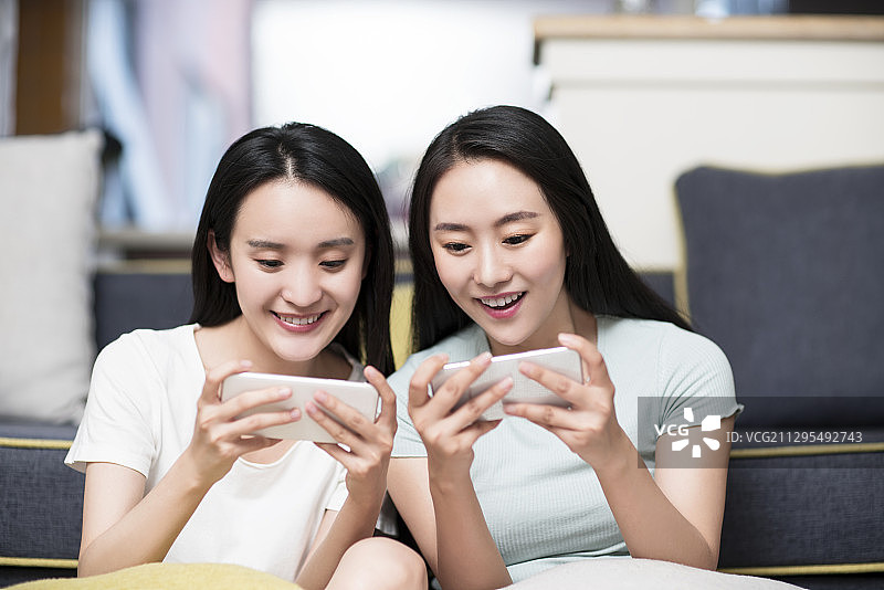 闺蜜在家使用智能手机玩游戏图片素材