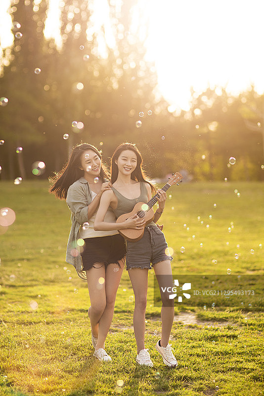 闺蜜在草地上开心的玩耍嬉戏图片素材