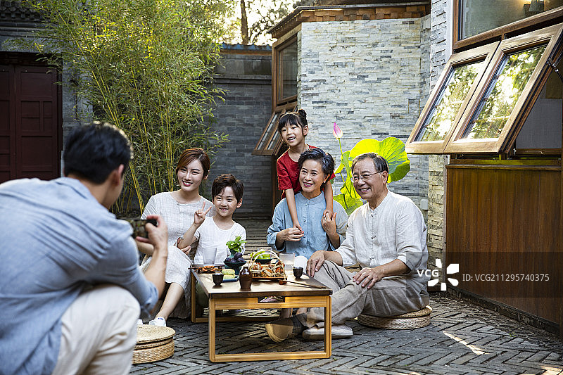 中秋节一家六口在户外庭院聚会用手机拍照合影图片素材