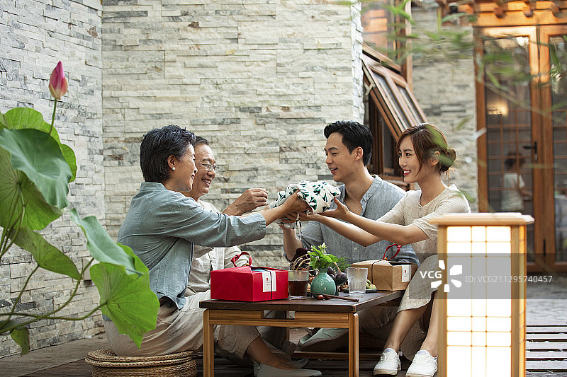 中秋节一家四口人在户外庭院聚餐送礼物图片素材