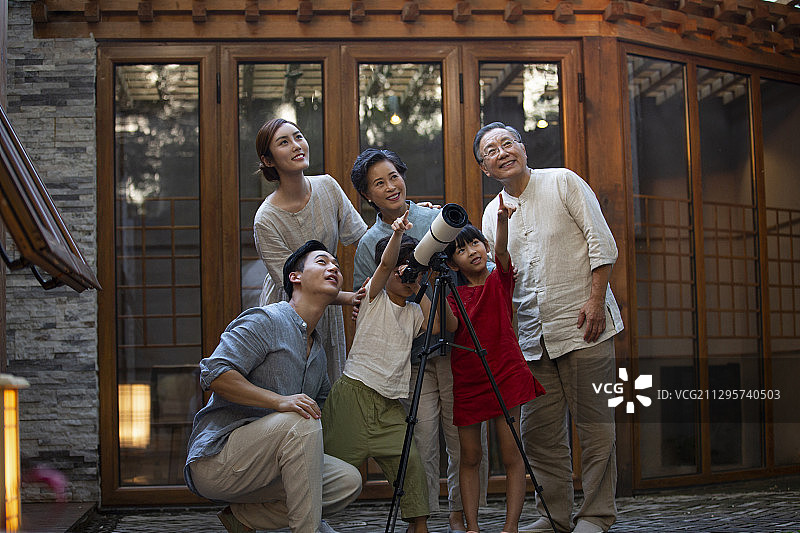 中秋节一家六口在户外庭院用天文望远镜看月亮图片素材