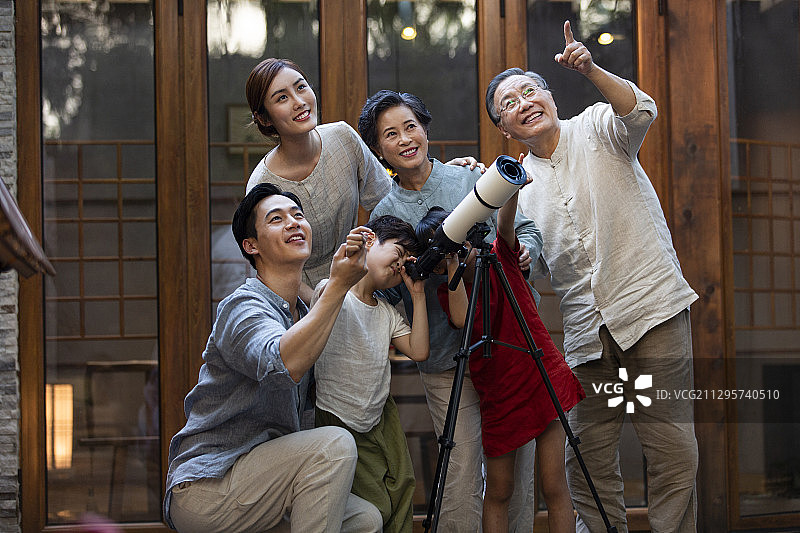 中秋节一家六口在户外庭院用天文望远镜看月亮图片素材