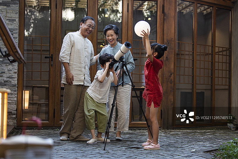 中秋节爷爷、奶奶和孙子、孙女在户外庭院用天文望远镜看月亮嬉戏图片素材