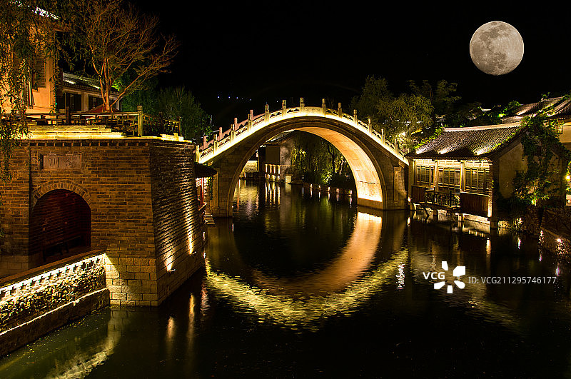 古镇夜晚灯光点缀的拱桥河流与民居图片素材
