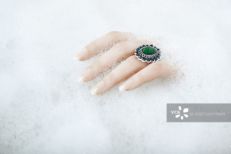 女人戴戒指的手在泡沫浴中图片素材