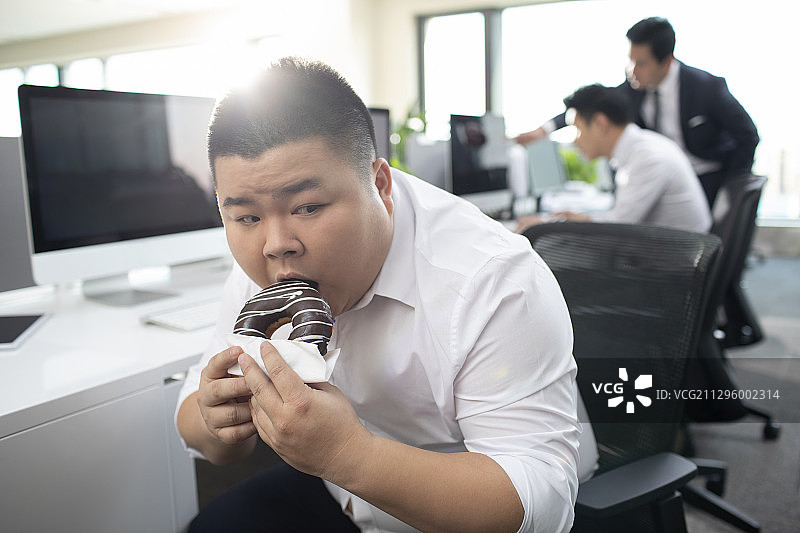 商务男士上班时间偷吃甜甜圈图片素材