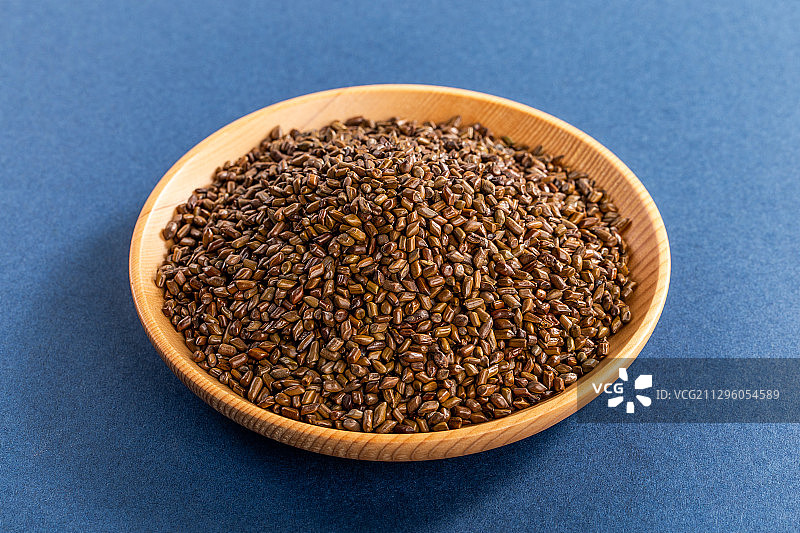 蓝色背景里摆放着满满一叠中药材决明子图片素材