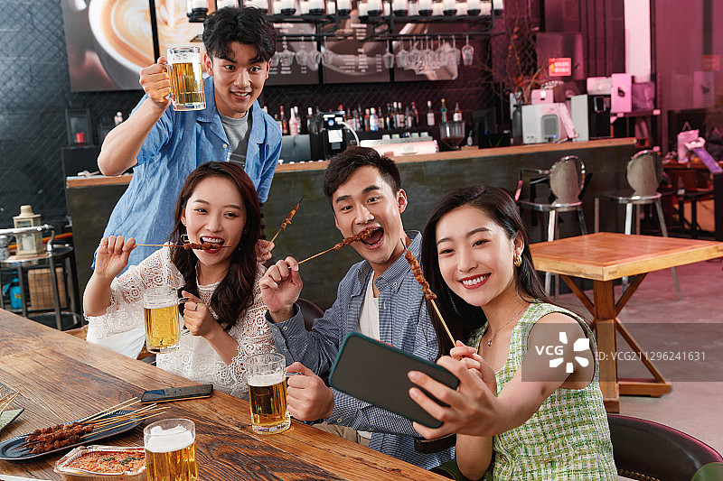 青年朋友边喝酒边拍照图片素材