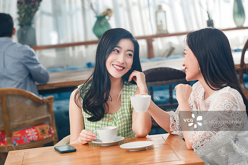 年轻闺蜜在咖啡馆聊天图片素材