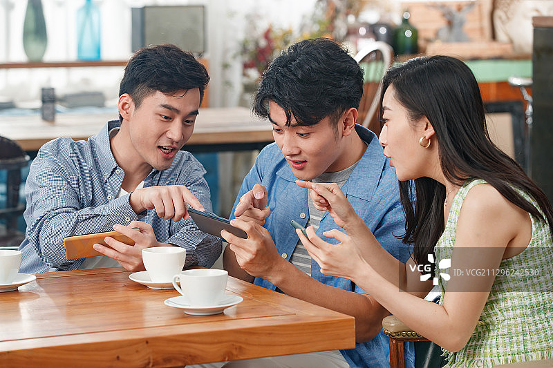 年轻朋友在咖啡馆里玩手机图片素材