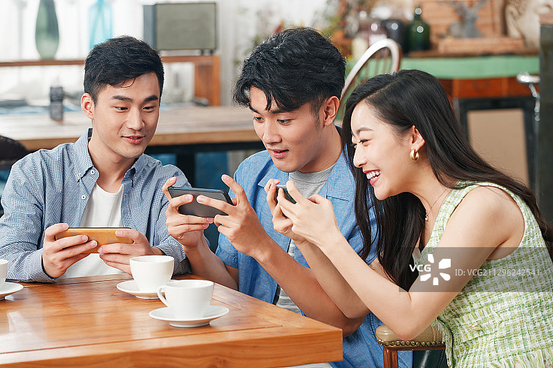 年轻朋友在咖啡馆里玩手机图片素材