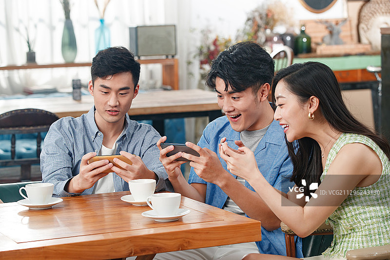 年轻朋友在咖啡馆里玩手机图片素材
