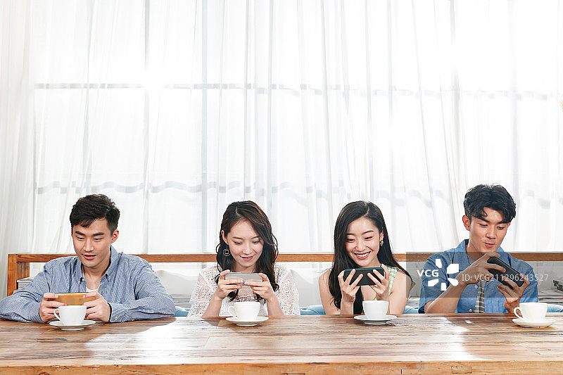 青年朋友坐在一排玩手机图片素材