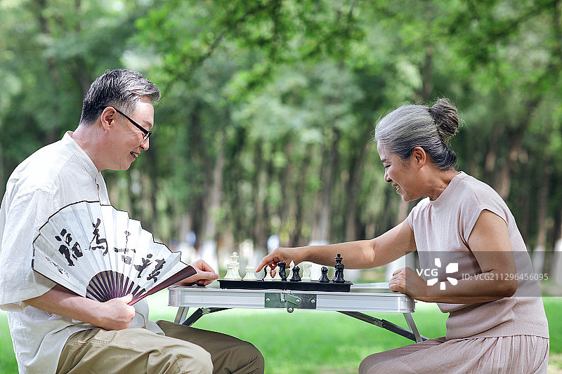 幸福的老年夫妇在公园下棋图片素材