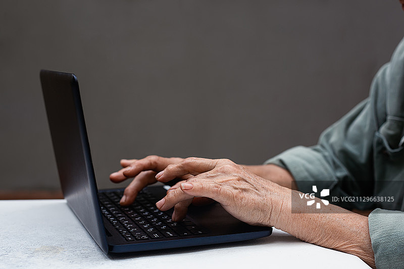 乌克兰敖德萨，使用笔记本电脑的老年妇女的腰部图片素材