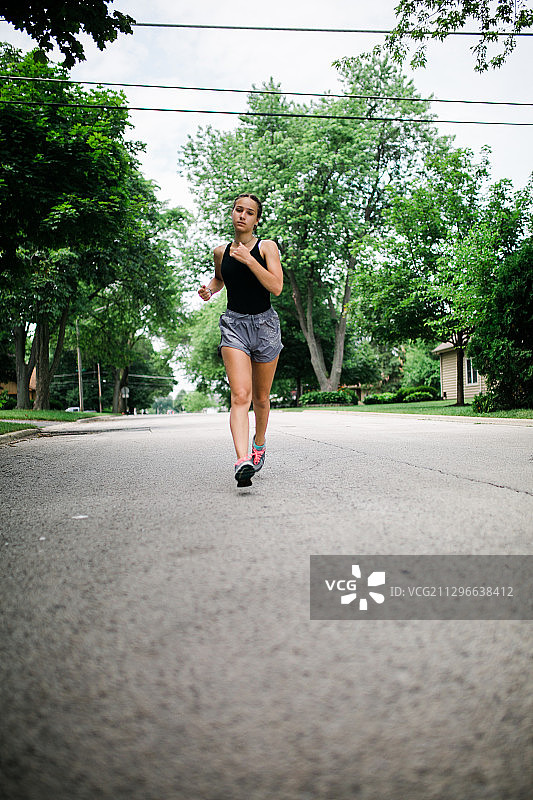 女子在树木间的道路上奔跑（美国阿灵顿高地）图片素材