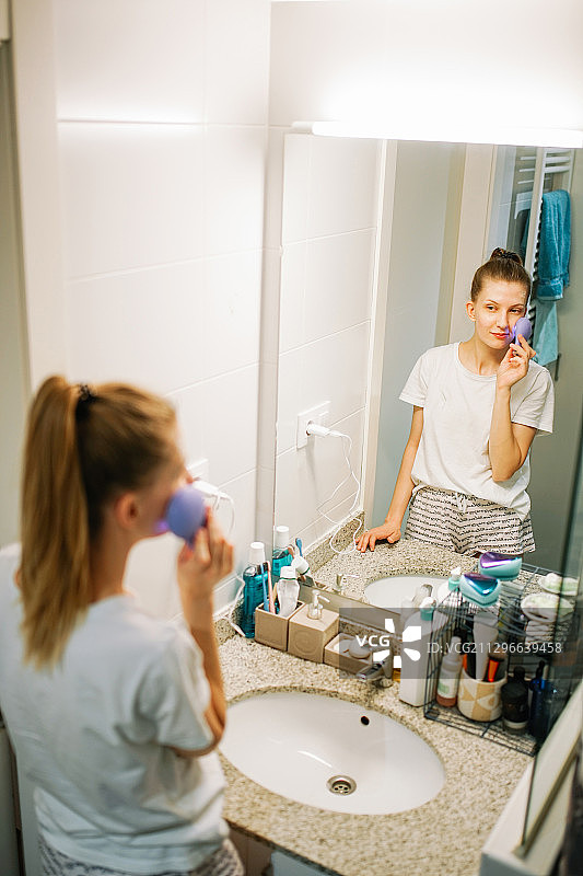 年轻女子在西班牙列伊达的浴室里用洁面仪洗脸图片素材