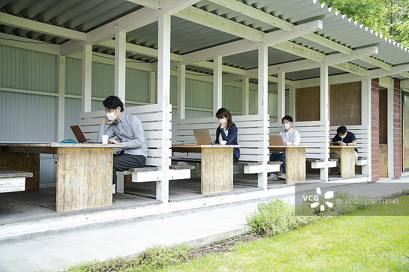 男人和女人在户外办公室工作，该办公室将社交距离设置为新常态办公风格图片素材