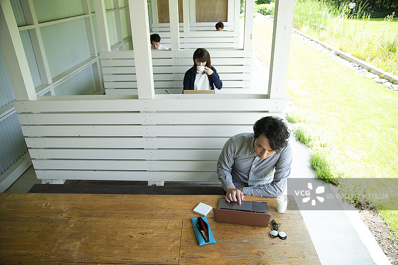 男人和女人在户外办公室工作，该办公室将社交距离设置为新常态办公风格图片素材