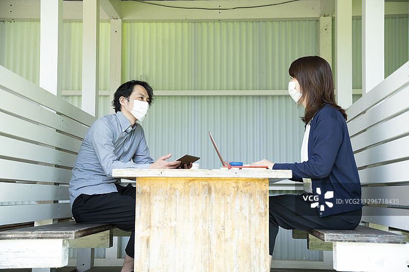 疫情新常态下，戴着口罩在户外办公室开会的年长男人和女人图片素材