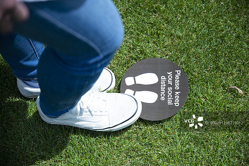 年轻男人的脚和社交距离标志图片素材