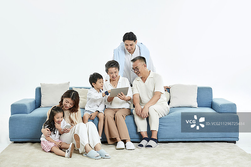 在客厅里看平板电脑与玩手机游戏视频的一家六口图片素材