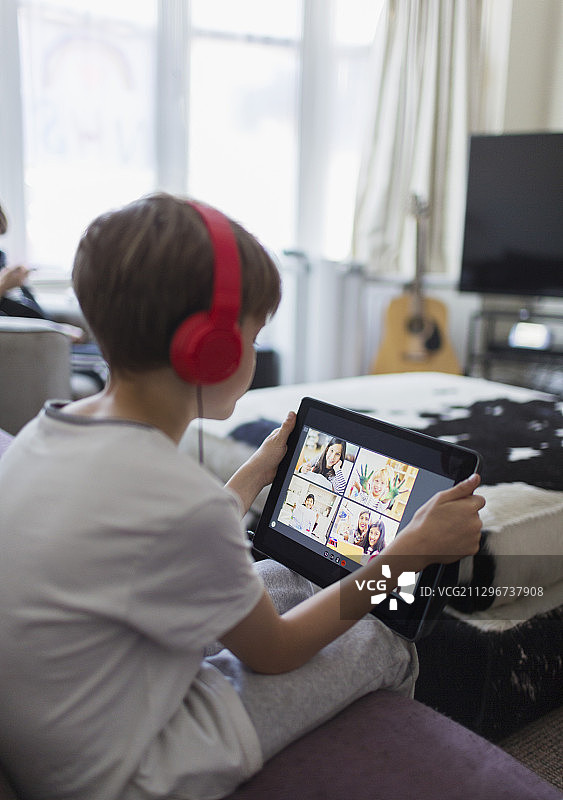 戴着耳机用平板电脑在家学习的男孩图片素材