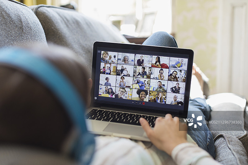 女人在沙发上通过笔记本电脑屏幕与朋友进行视频聊天图片素材
