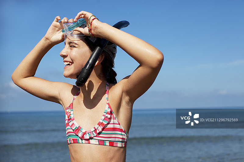 在海滩上戴着呼吸管和护目镜的微笑女孩图片素材