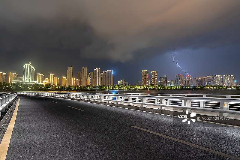 带灯光的柏油路及划过一道闪电的城市夜景天际线图片素材