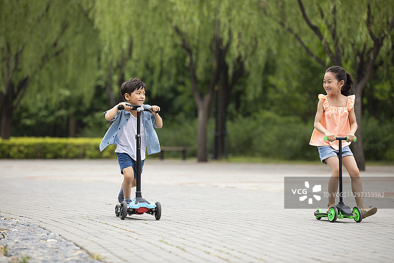 快乐的孩子们在公园骑滑板车图片素材