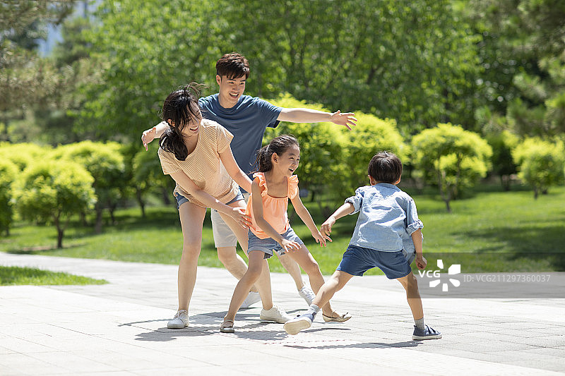 快乐的年轻家庭在公园玩耍图片素材