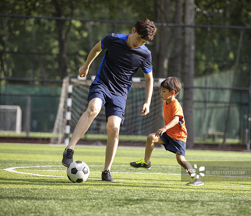 父子俩在足球场踢足球图片素材