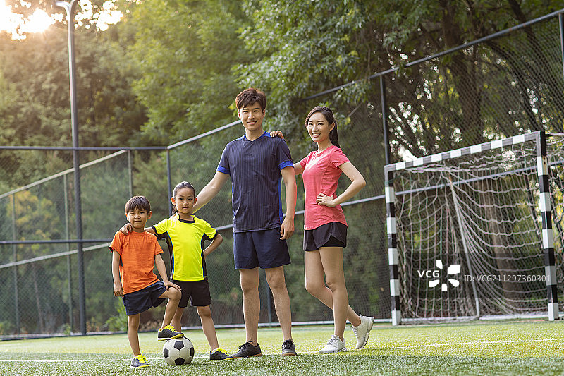 快乐的年轻家庭在足球场踢足球图片素材