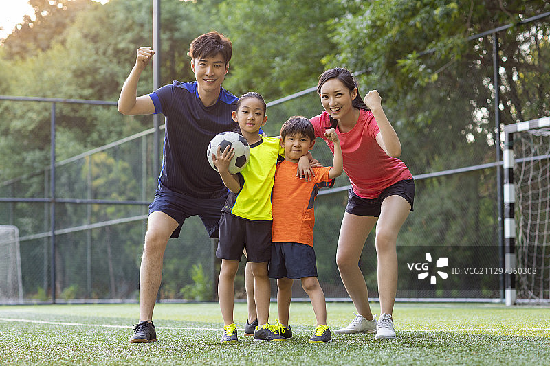 快乐的年轻家庭在足球场踢足球图片素材