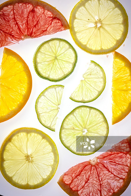 白色背景上各种背光柑橘切片的抽象构图图片素材