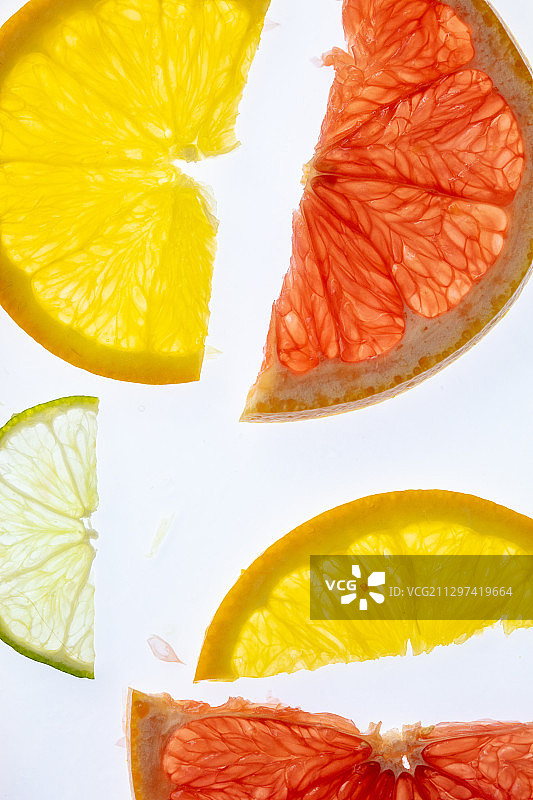 白色背景上各种背光柑橘切片的抽象构图图片素材