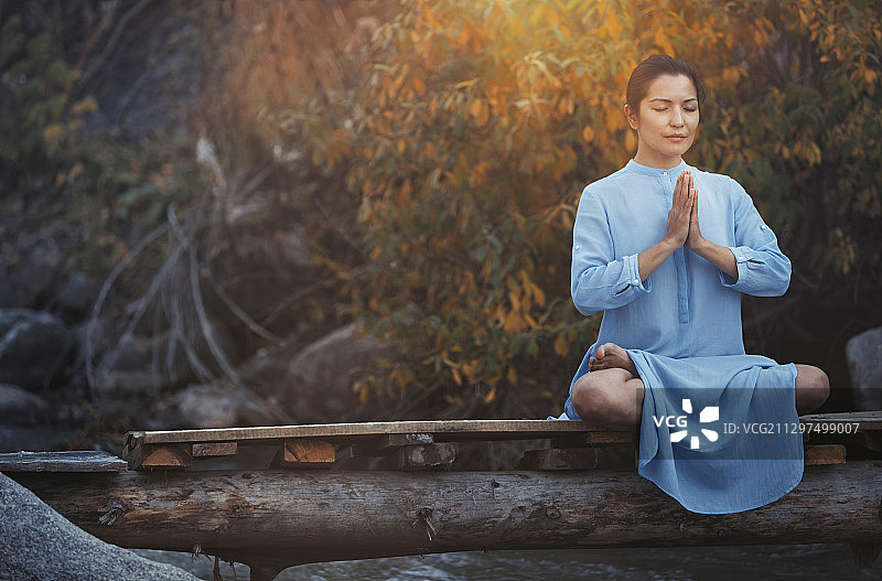 女人在瀑布桥上莲花坐冥想图片素材