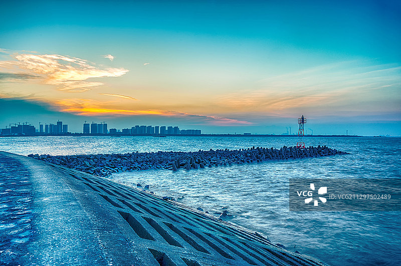 日落时分，太仓浏河口深入长江的丁坝和江堤，红白相间的灯塔图片素材