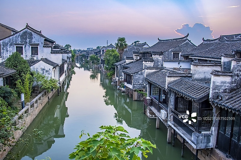 落日余晖中的太仓沙溪古镇，河道中倒影出蓝紫色的天空和万道霞光图片素材
