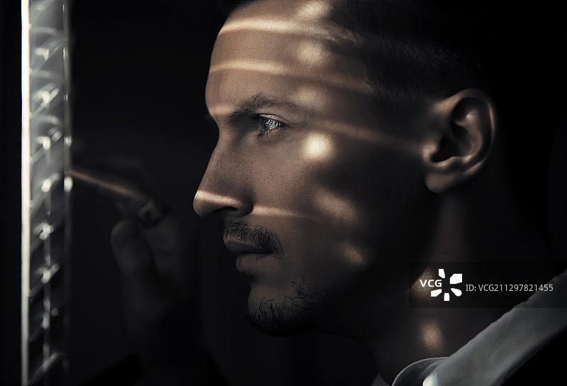 透过百叶窗向外看的英俊时尚男士图片素材