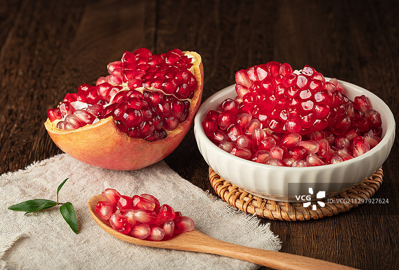 暗调木桌勺子剥好的软籽石榴果实图片素材