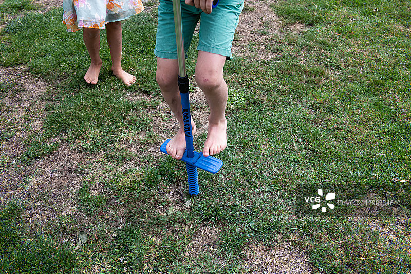 小男孩在草地上玩弹簧单高跷图片素材