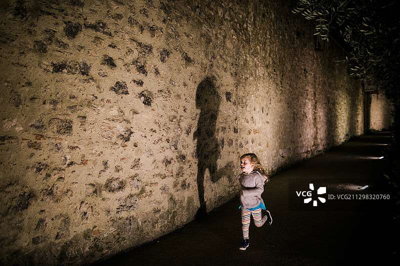 一位年轻女孩在意大利圣吉米尼亚诺的城墙上奔跑图片素材
