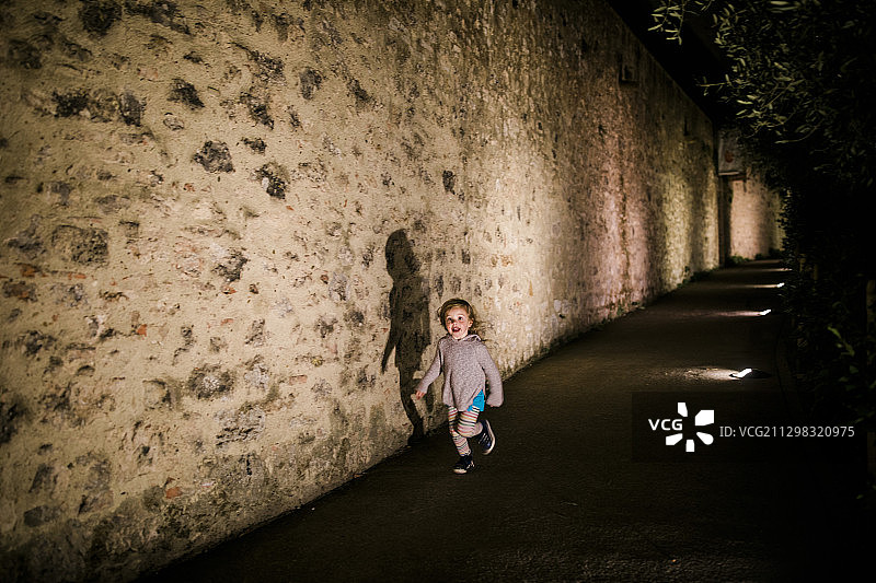 一位年轻女孩在意大利圣吉米尼亚诺的城墙上奔跑图片素材