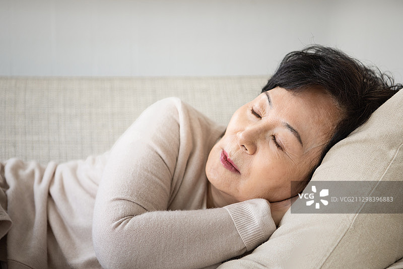 年长的女人躺在沙发上睡觉图片素材