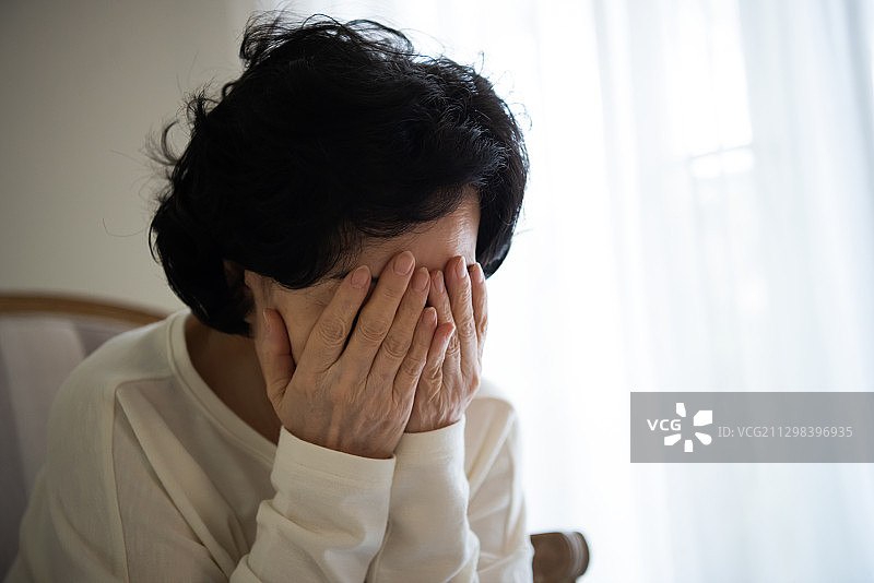 妇女坐在椅子上用手捂着脸图片素材