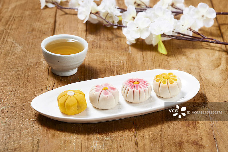 日式茶杯旁摆放着带有花卉图案的传统日式甜点图片素材