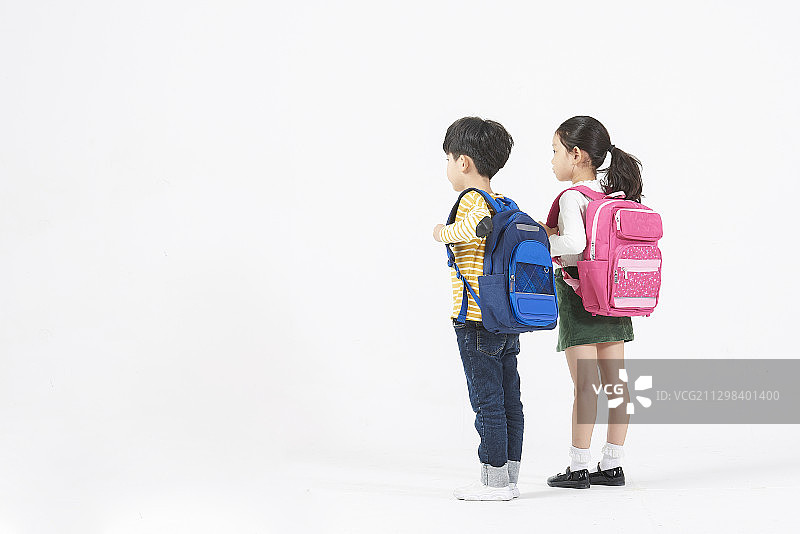 站在白色背景上的背着背包的男孩和女孩的后视图图片素材