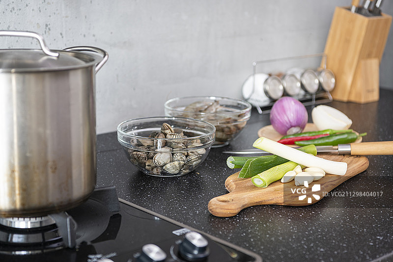 燃气灶旁的烹饪食材：虾、蛤蜊和蔬菜图片素材